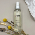 Bottle of petal brightening facial mist with flowers and herbs on a neutral background